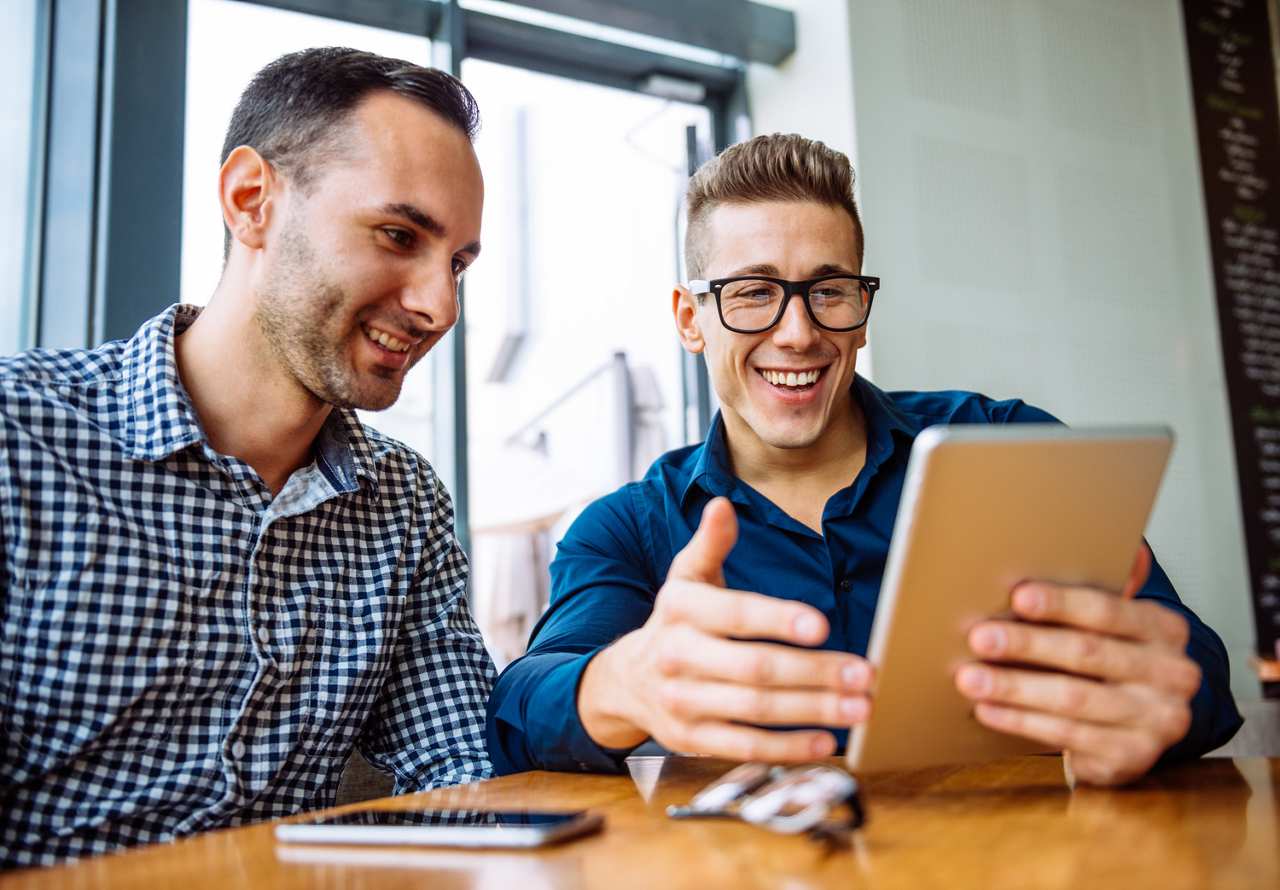 Two casual men using a tablet.