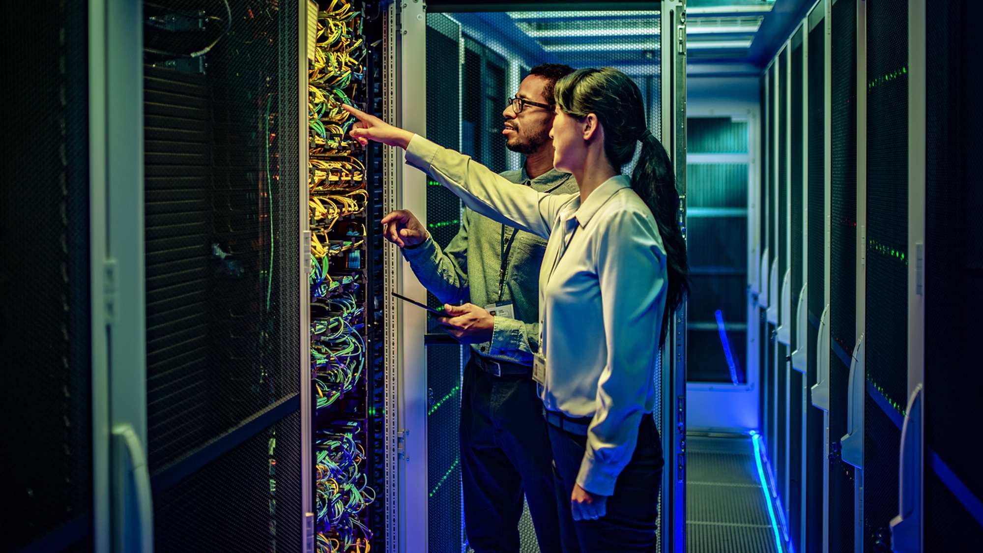 two people standing in front of a server in a data center