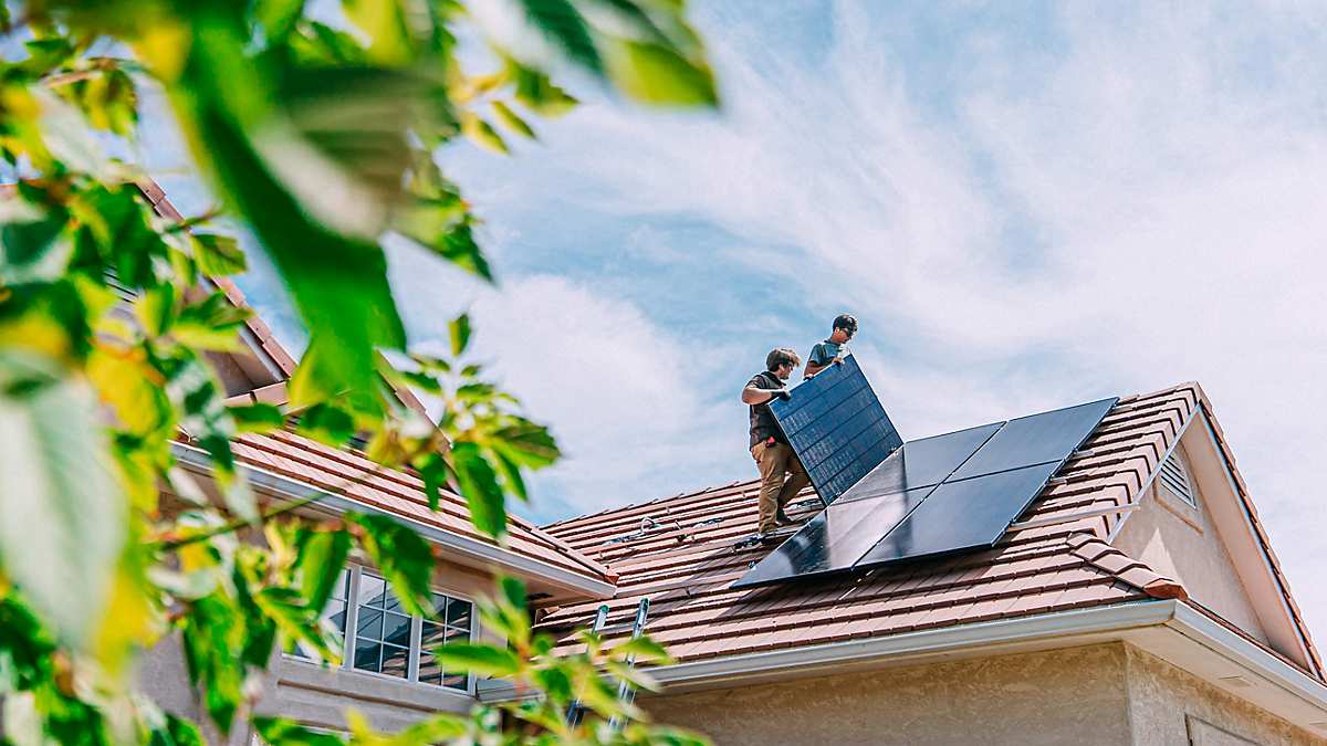 屋根にソーラーパネルを設置する住宅所有者