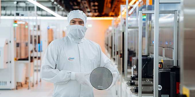 A technical engineer in the cleanroom at Infineon Technologies in Villach, Austria, holds a 200 mm silicon carbide wafer.