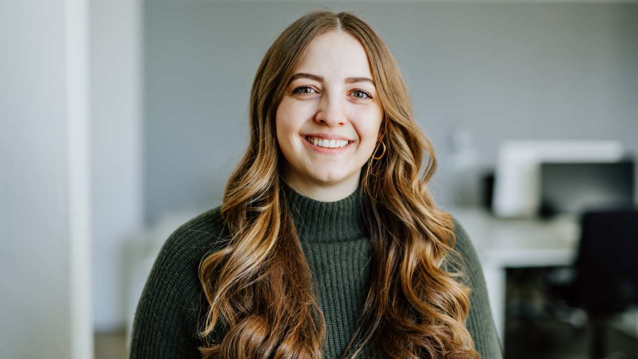 A woman in a green sweater in an office environment.