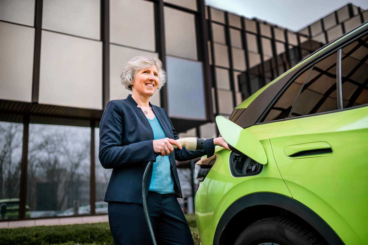 Valeo employee leaning against a green electric car.
