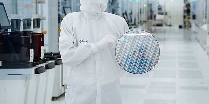 A technical engineer in the cleanroom at Infineon Technologies in Villach, Austria, holds a 300 mm gallium nitride wafer.