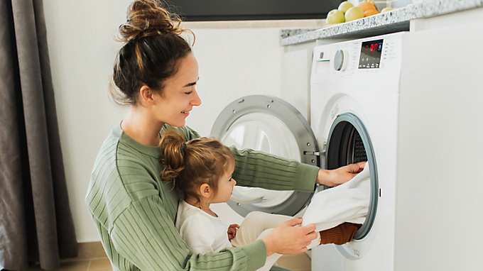 Mother with child loading washing machine