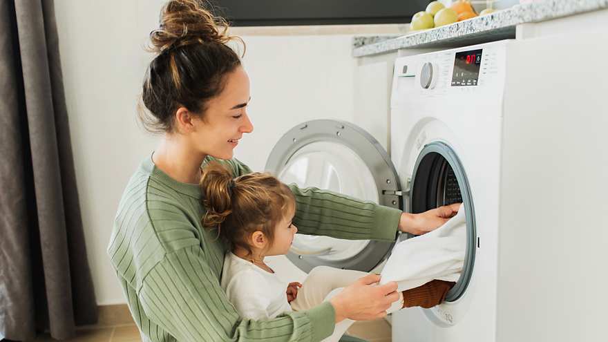 Mother with child loading washing machine
