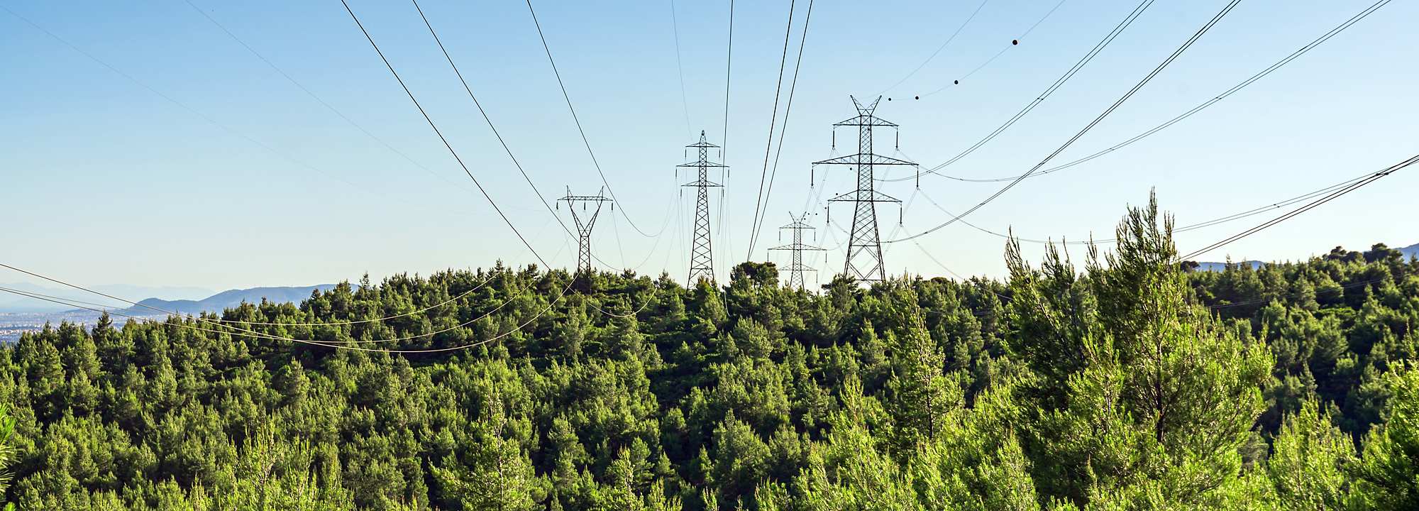 A backdrop of natural surroundings features alongside several transmission towers.