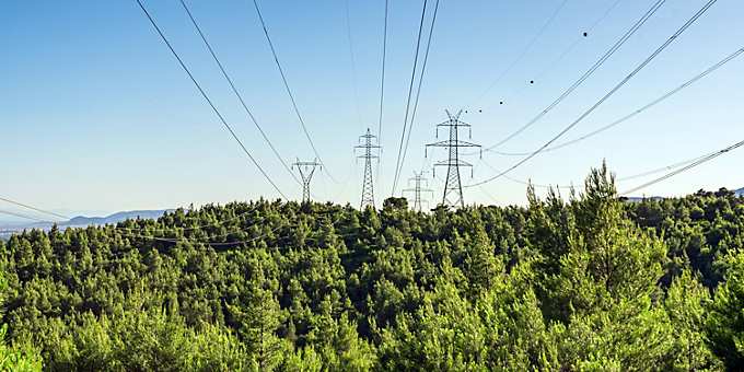 A backdrop of natural surroundings features alongside several transmission towers.